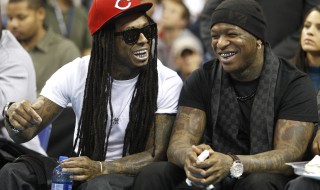 New Orleans rapper Lil Wayne sits with Birdman during the New Orleans Hornets NBA basketball game against the Miami Heat in New Orleans
